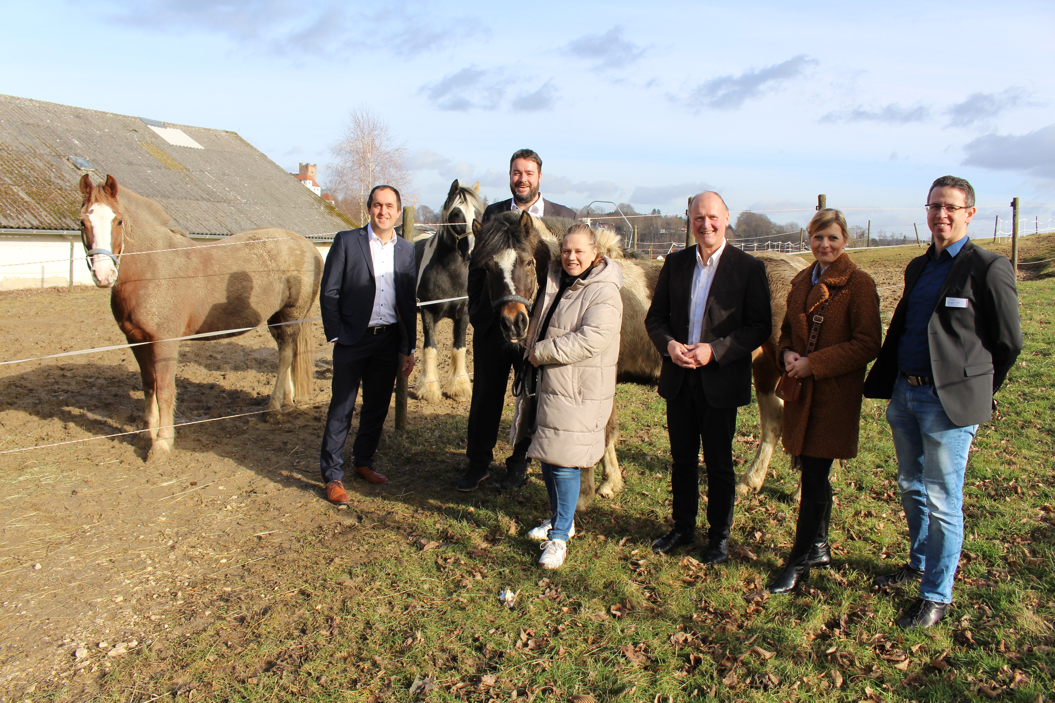 Sie freuten sich über den neuen Pachtvertrag, mit dem das Therapeutische Reiten auf dem Gelände des Bezirkskrankenhauses Günzburg weiter angeboten werden kann: (von links) Stefan Brunhuber (Vorstandsvorsitzender Bezirkskliniken Schwaben), Karsten Zanor (Vorstand Lebenshilfe Donau-Iller), Annelies Eggers (Einrichtungsleiterin), Dr. Johann Popp (stellvertretender Verwaltungsratsvorsitzender der Bezirkskliniken), Sonja Treffler (Krankenhausreferentin Bezirk Schwaben), Benjamin Englert (Regionalleiter Nord Bezirkskliniken). Im Hintergrund sind die Pferde der Lebenshilfe Majesty, Sahra und Pony Hanni zu sehen. Bild: Georg Schalk, Bezirkskliniken Schwaben