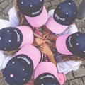 Kinder mit Cappys stecken ihre Köpfe im Kreis zusammen.