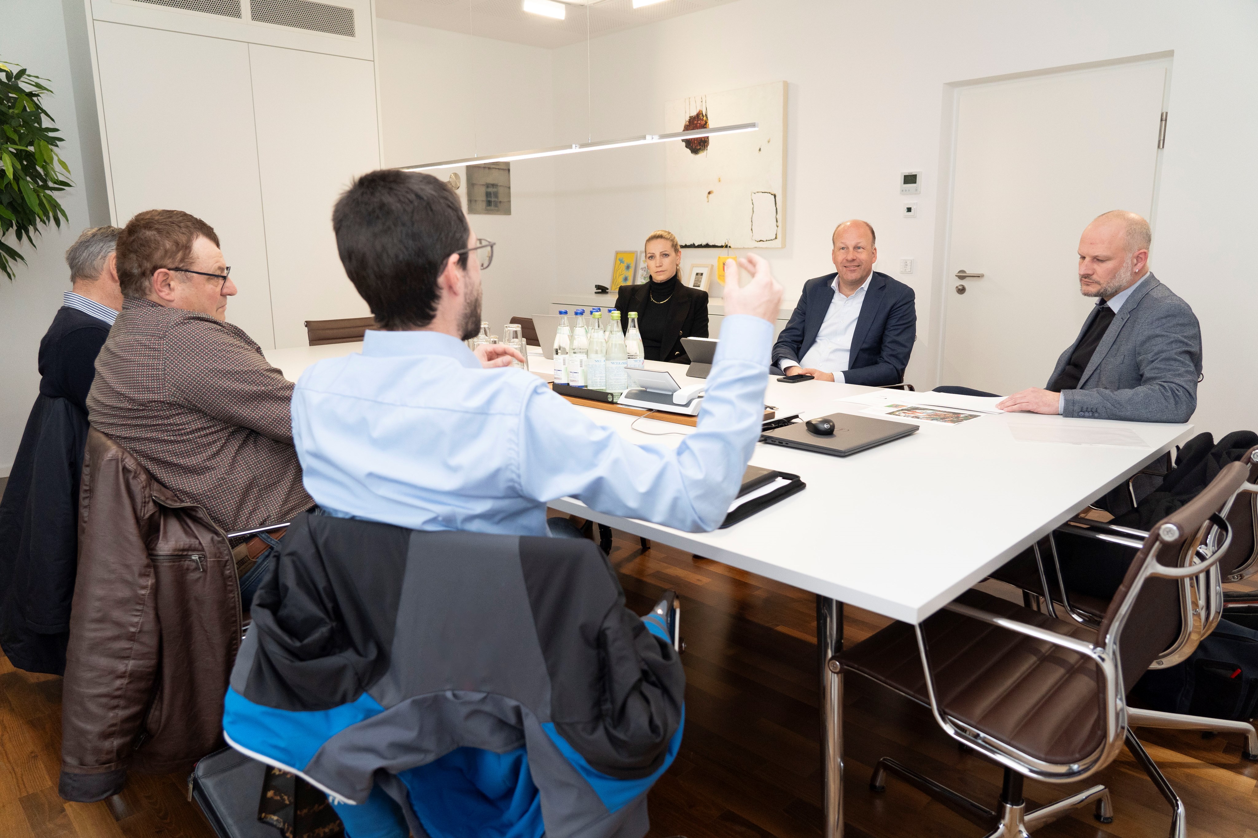 sechs Menschen an einem Tisch diskutieren