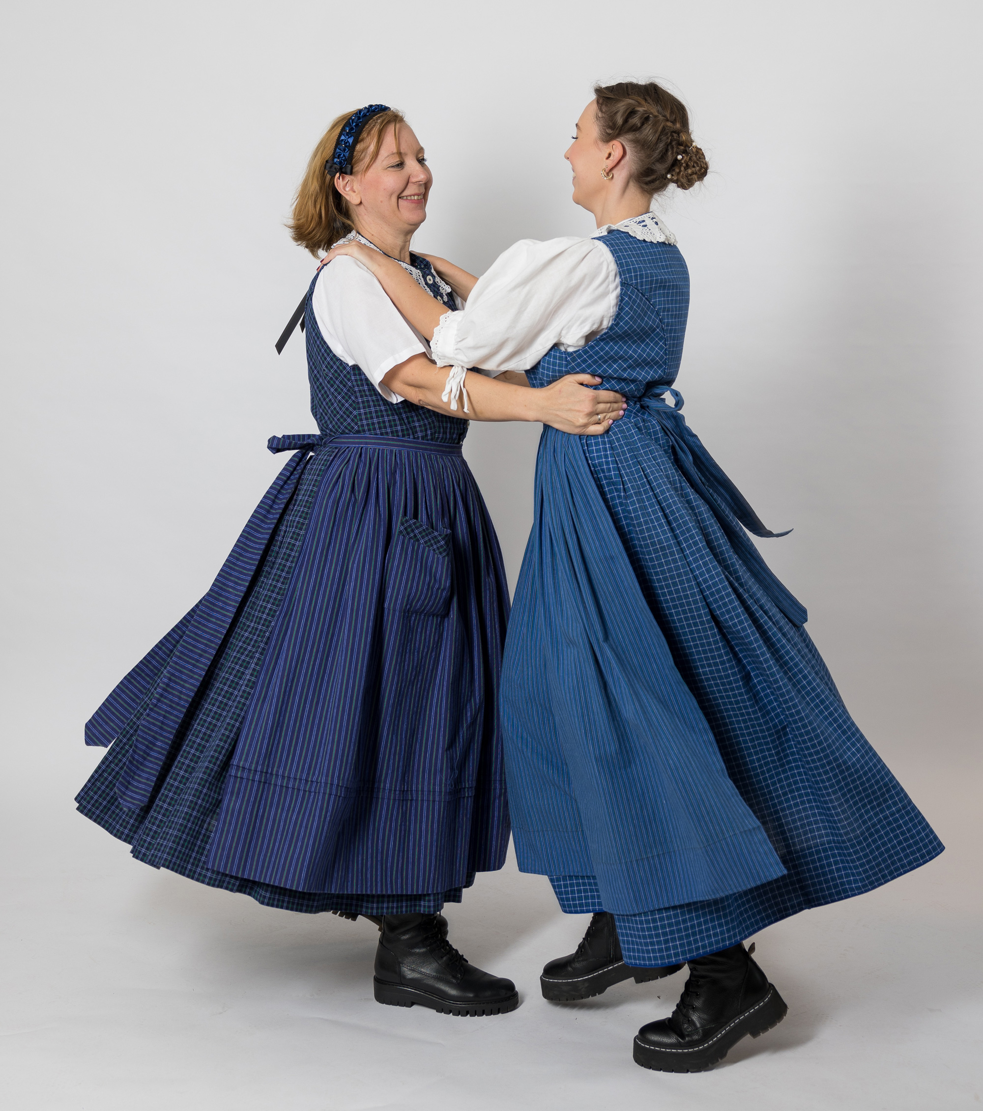 Zwei Frauen im blauen Werktagsgwand tanzen miteinander.