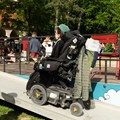 Mann im Rollstuhl benutzt Rampe für Rollstuhlfahrer