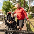 Mann im Rollstuhl posiert mit einem anderen Mann vor einer Bühne