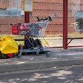 Wohnungsloser schläft am Boden einer Haltestelle, davor Einkaufwagen