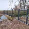 Zaun, der über Land und durch einen Bachlauf führt