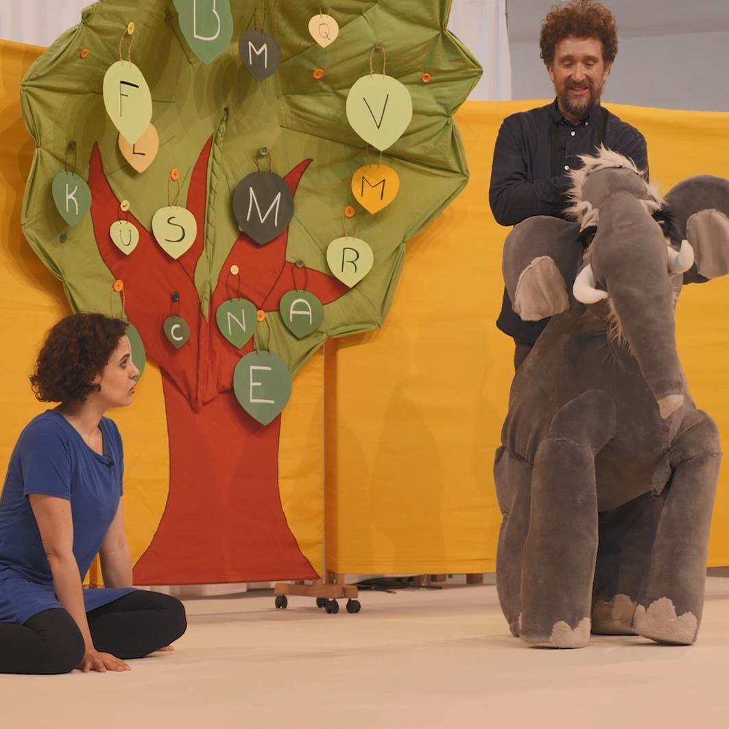 Theaterszene mit Baum, Frau, Mann und Stofftierelefant