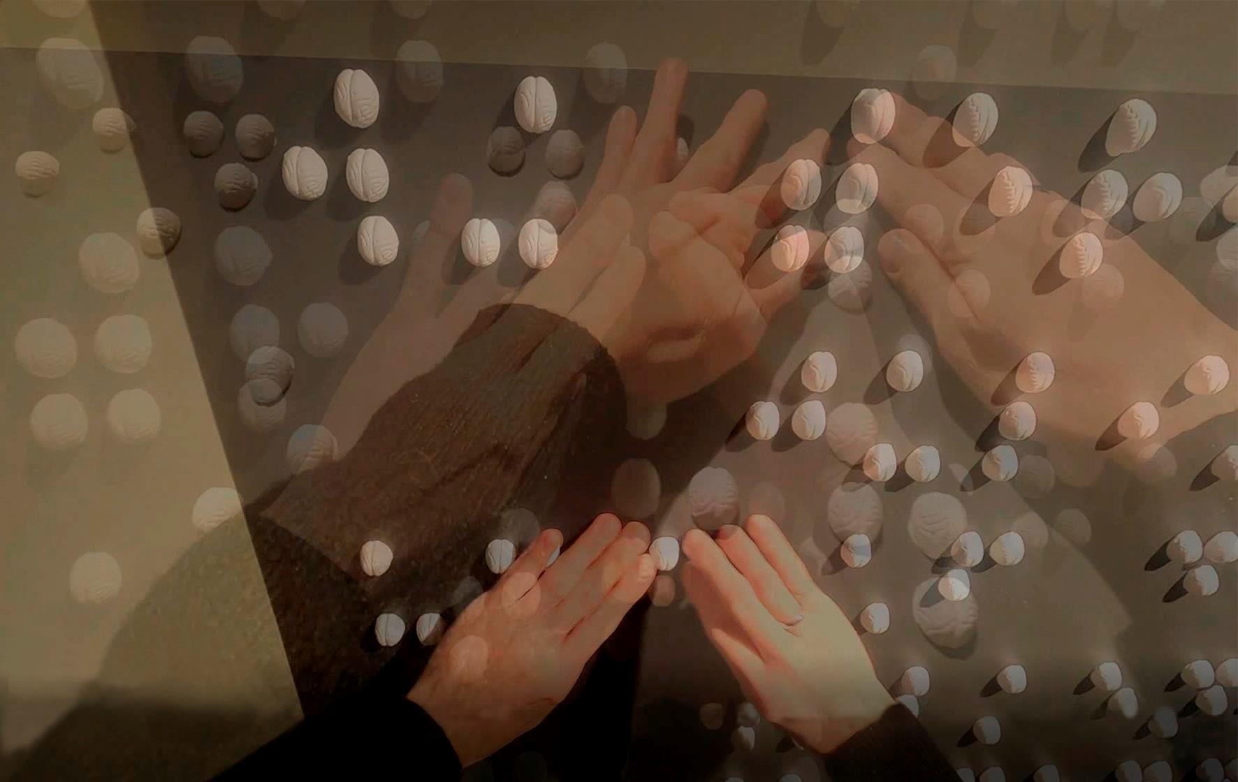 Finger tasten über weiße Noppen in Braille-Schrift