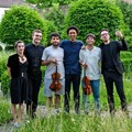 Fünf Musiker und eine Schauspielerin stehen nebeneinander im Grünen