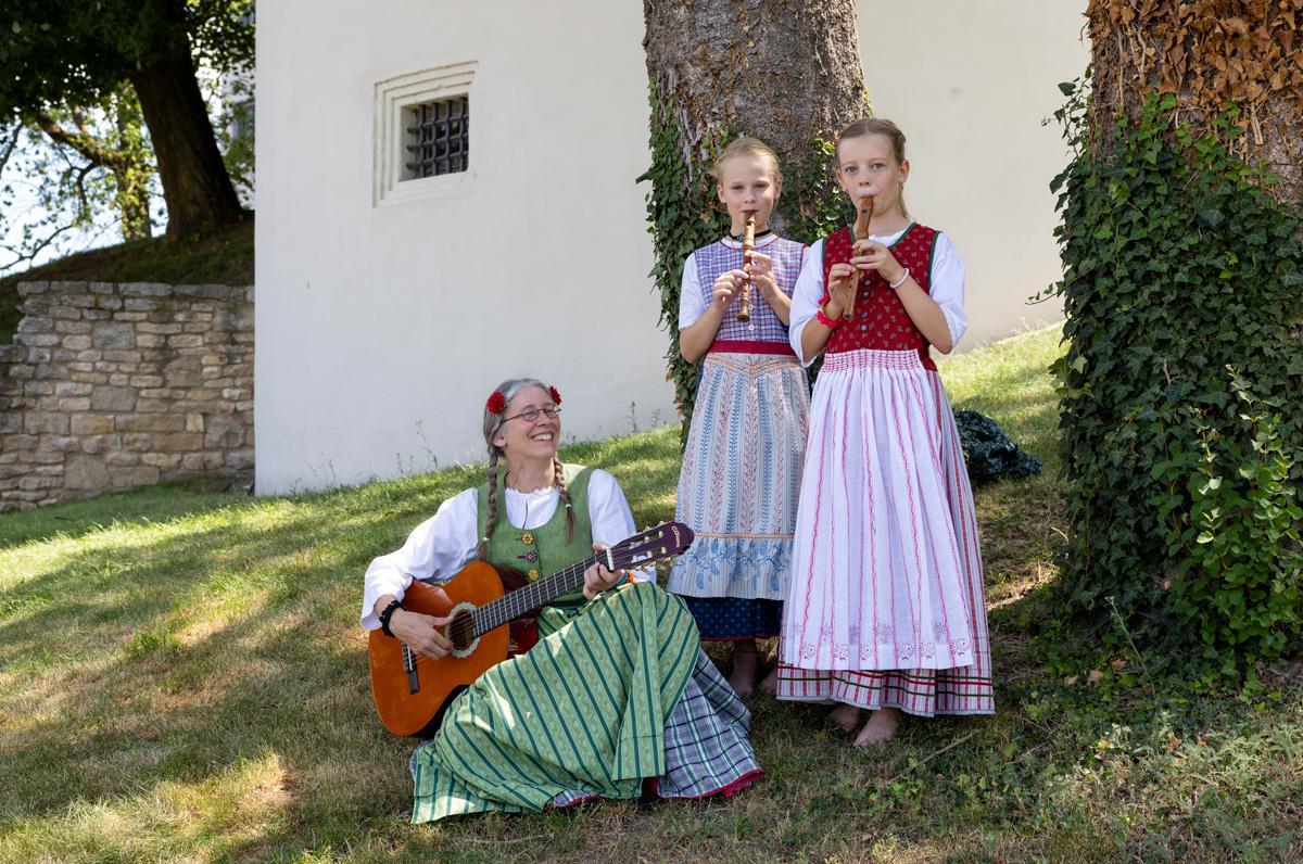 Eine Frau und zwei Mädchen im Werktagsgwand beim Musizieren