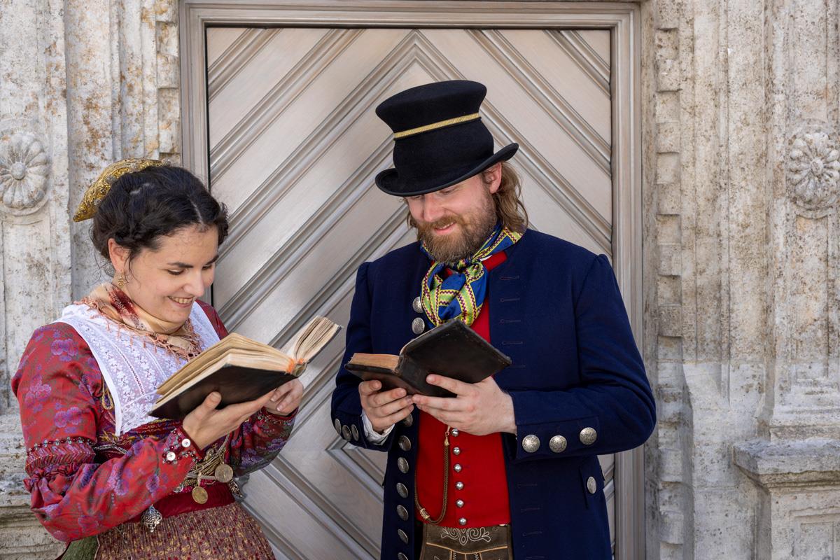 Eine Frau und ein Mann in Biedermeiertracht beim Lesen