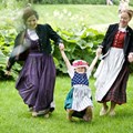 Zwei Frauen in Kitteljacke mit einem Kind in der Mitte