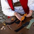 Ein Mann hält einen Posamentenbesatz in der Hand.