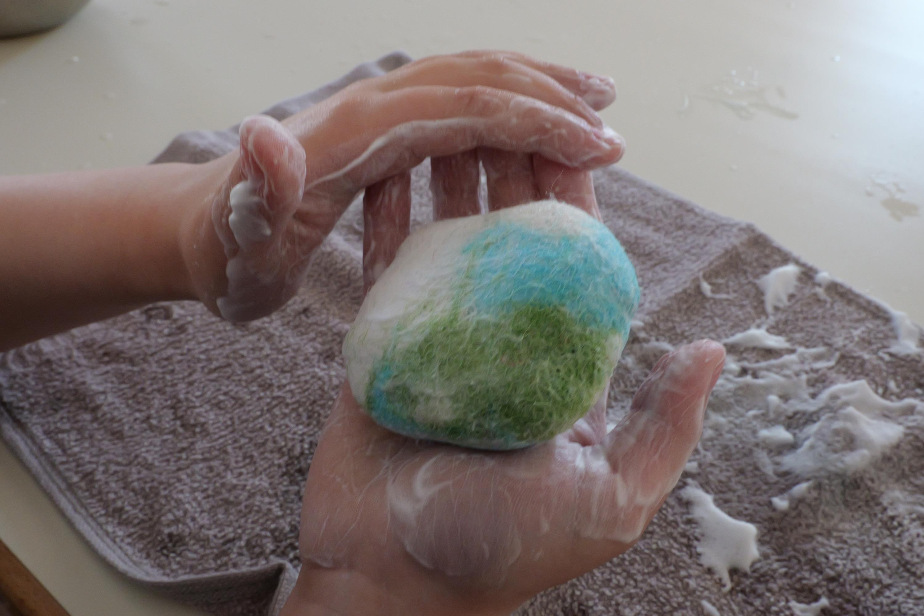 Zwei Hände umfilzen ein kleines Stück Seife