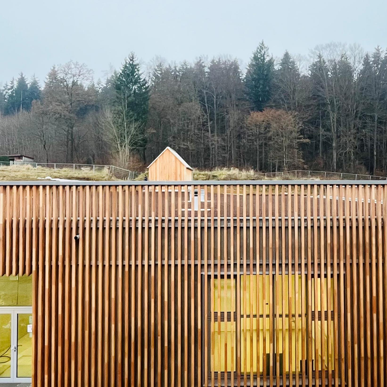 Holzverkleidete Fassade mit Bäumen im Hintergrund
