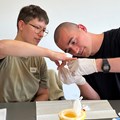 ein Mann mit Gummihandschuhen untersucht die Hand eines anderen Mannes