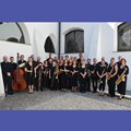 schwarz gekleidete Musiker mit Instrumenten vor weißem Gebäude
