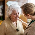 Seniorin lächelt eine Frau an, diese legt eine Hand auf ihre Schulter