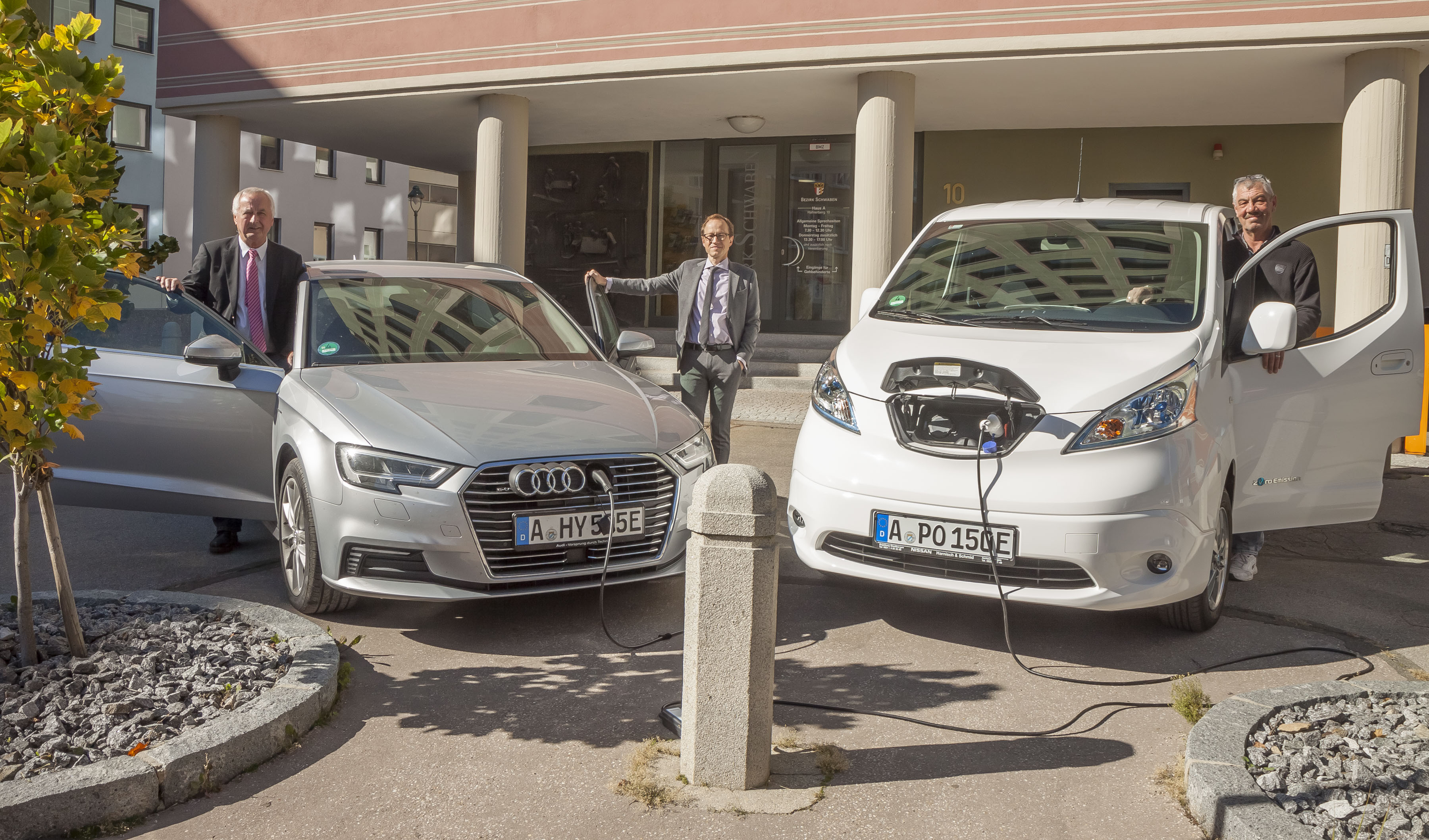 Bezirkstagspräsident Jürgen Reichert und Kämmerer Martin Seitz am Hybrid-Auto, Poststellen-Mitarbeiter Hermann Wiedemann am Elektroauto