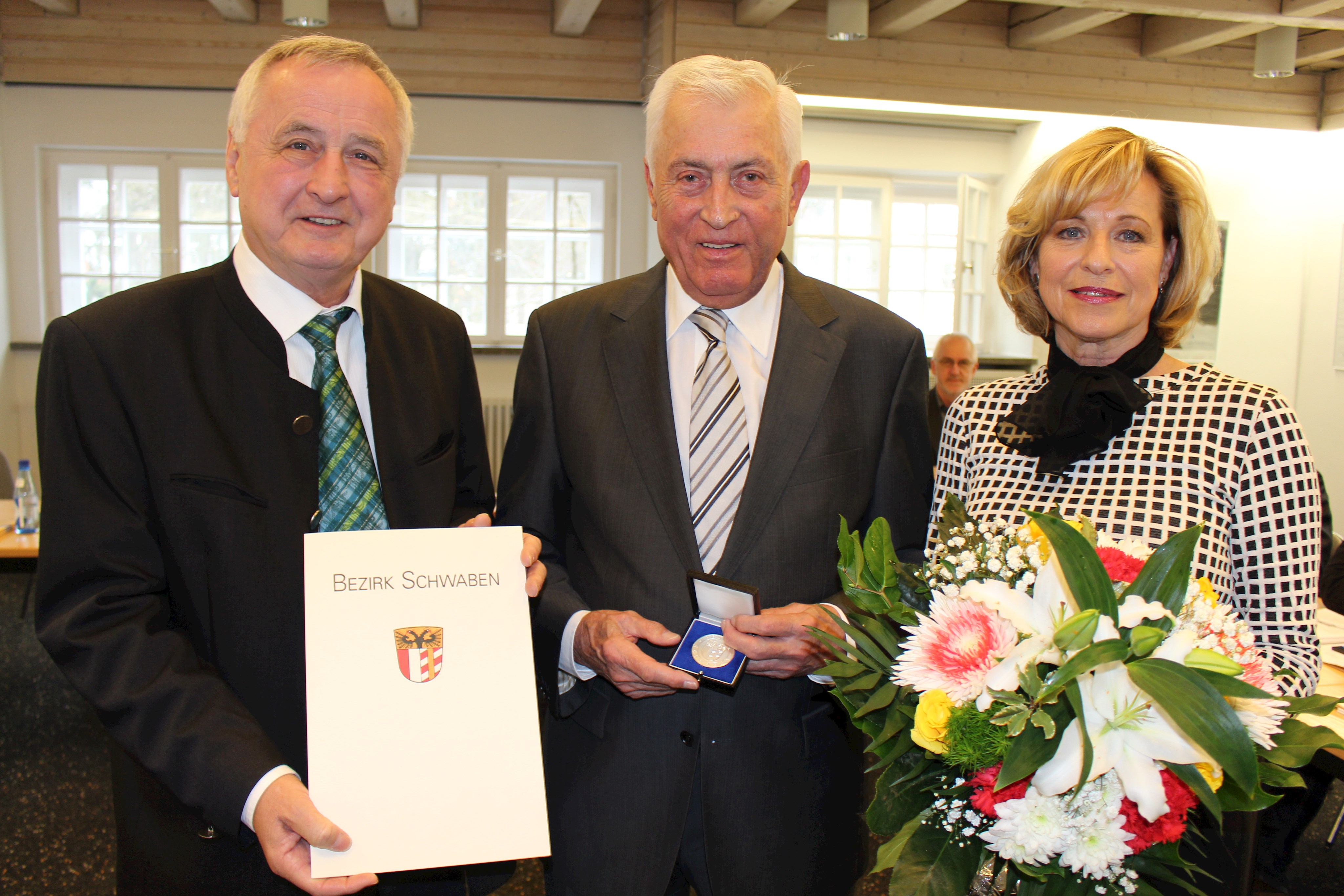 Bezirkstagspräsident Jürgen Reichert bei der Verleihung der Bezirksmedaille an Max Schuster, dessen Ehefrau Veronika sich mit freute über die hohe Auszeichnung (im Bild von links).