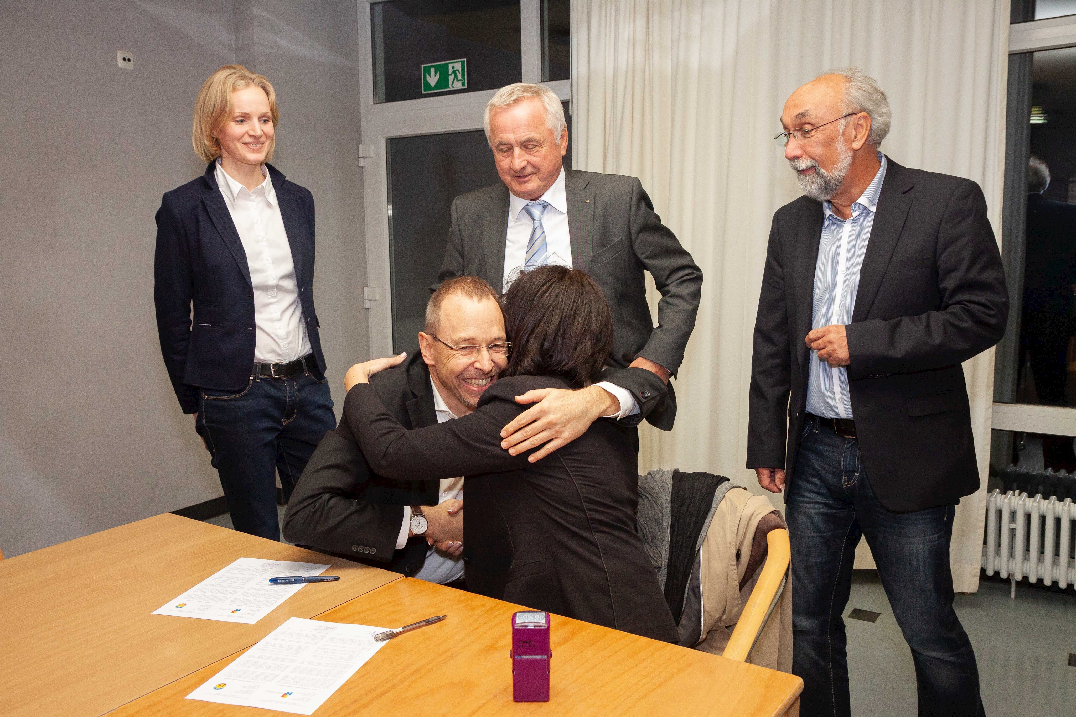 Gregor Beck und Tetiana Zakrutna beglückwünschen sich der Vertragsunterzeichnung mit einer Umarmung.