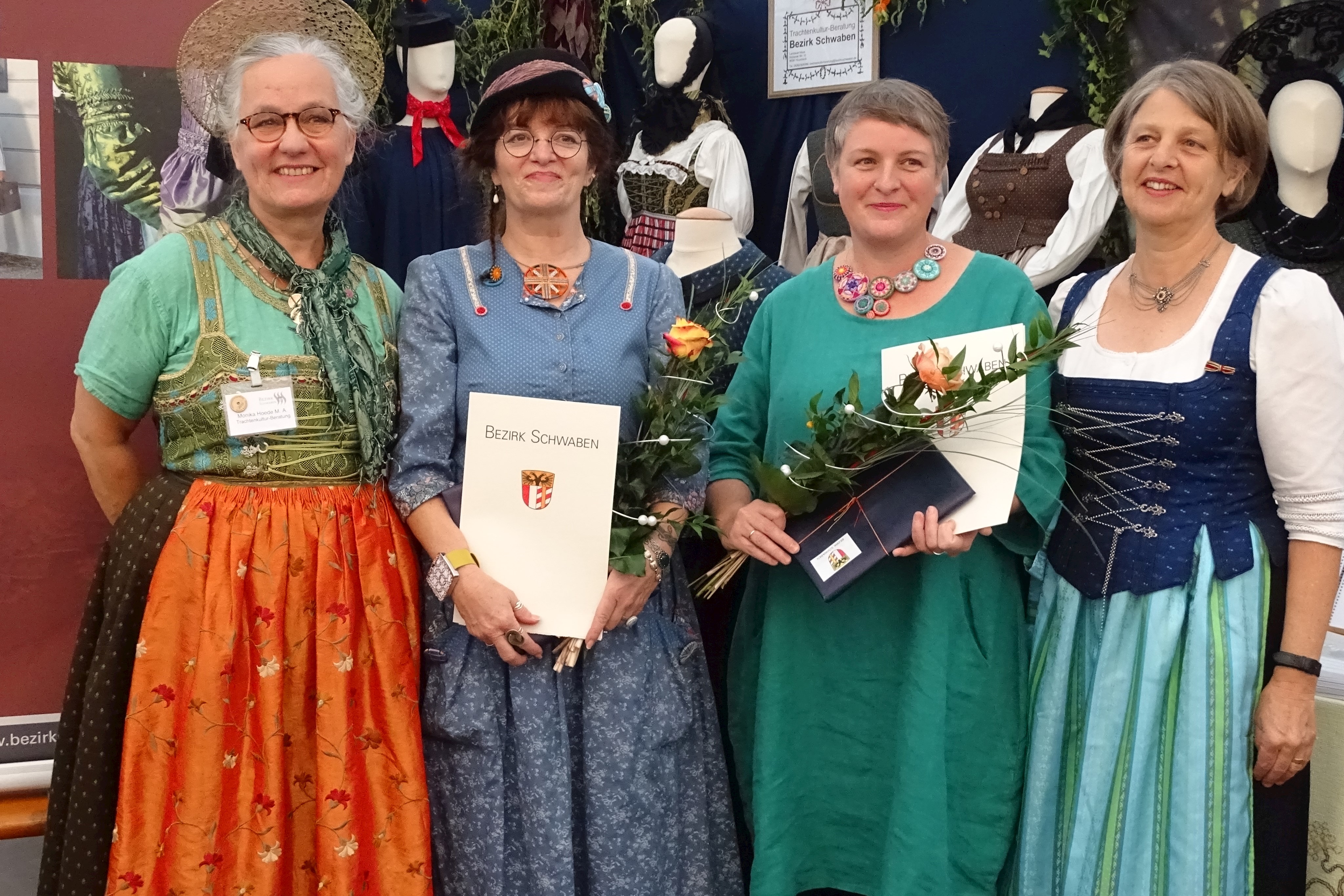 von rechts nach links: Vizebezirkstagspräsidentin Barbara Holzmann, Jutta Kohlbeck, Ursula Sauer, Trachtenberaterin Monika Hoede. 
Jutta Kohlbeck aus Regensburg ist Künstlerin: Zeichnungen, Quilts und seit zwei Jahren nun auch Posamentenknopfkreationen zeigt sie in Social Media und in vielbeachteten Ausstellungen. Ursula Sauer ist stolz darauf, sich der Herausforderung gestellt zu haben, nochmal eine anspruchsvolle Prüfung zu bestehen und trägt ihre kreativen Knopfwerke immer und überall. In drei Jahren haben inzwischen zwölf Prüflinge das Knopfmacherzertifikat erhalten.