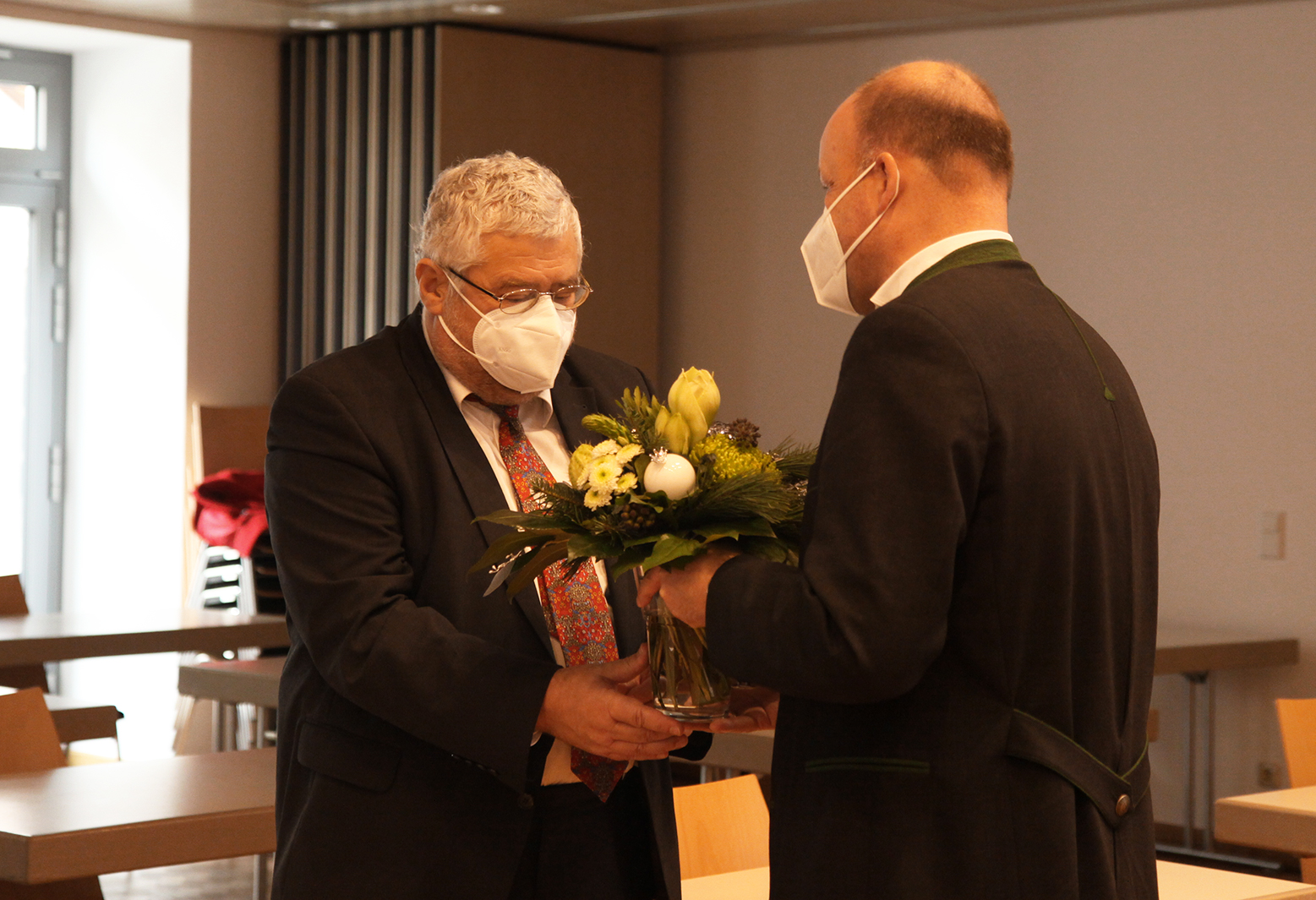 Bezirkstagspräsident überreicht Dr. Peter Fassl einen Blumenstrauß im Rahmen der Bezirkstagssitzung.