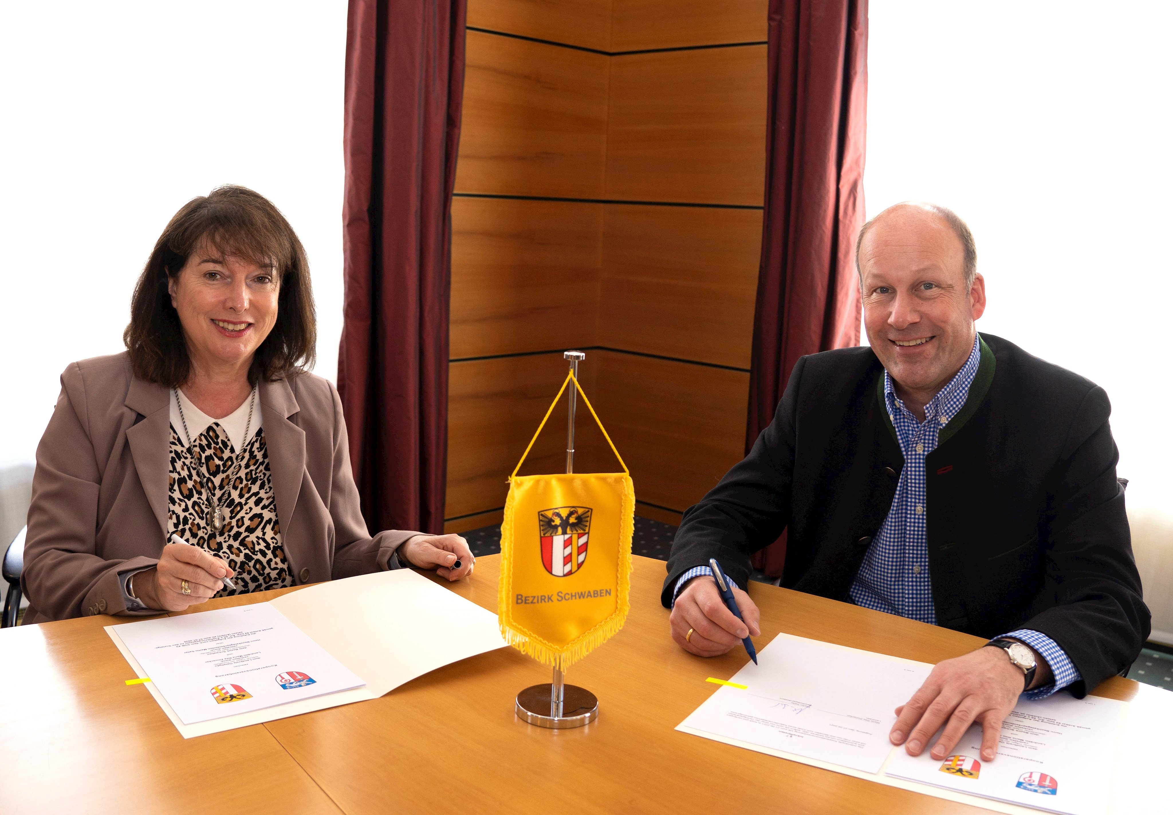 Bezirkstagspräsident Martin Sailer und Landrätin Maria Rita Zinnecker unterzeichnen die Kooperationsvereinbarung