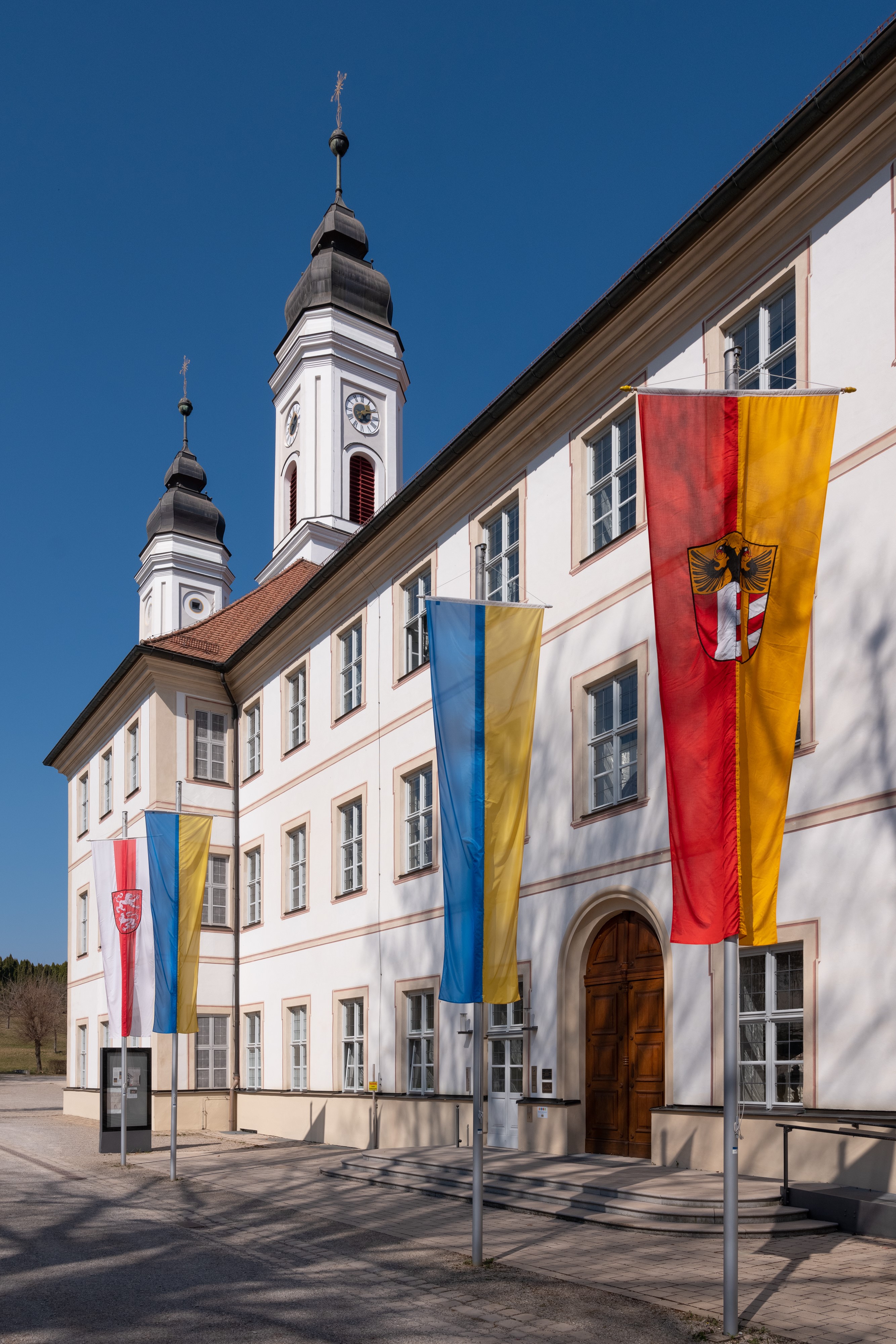 Die Fahnen der Ukraine, des Bezirks Schwaben und des Marktes Irsee vor der Irseer Klosterfassade.