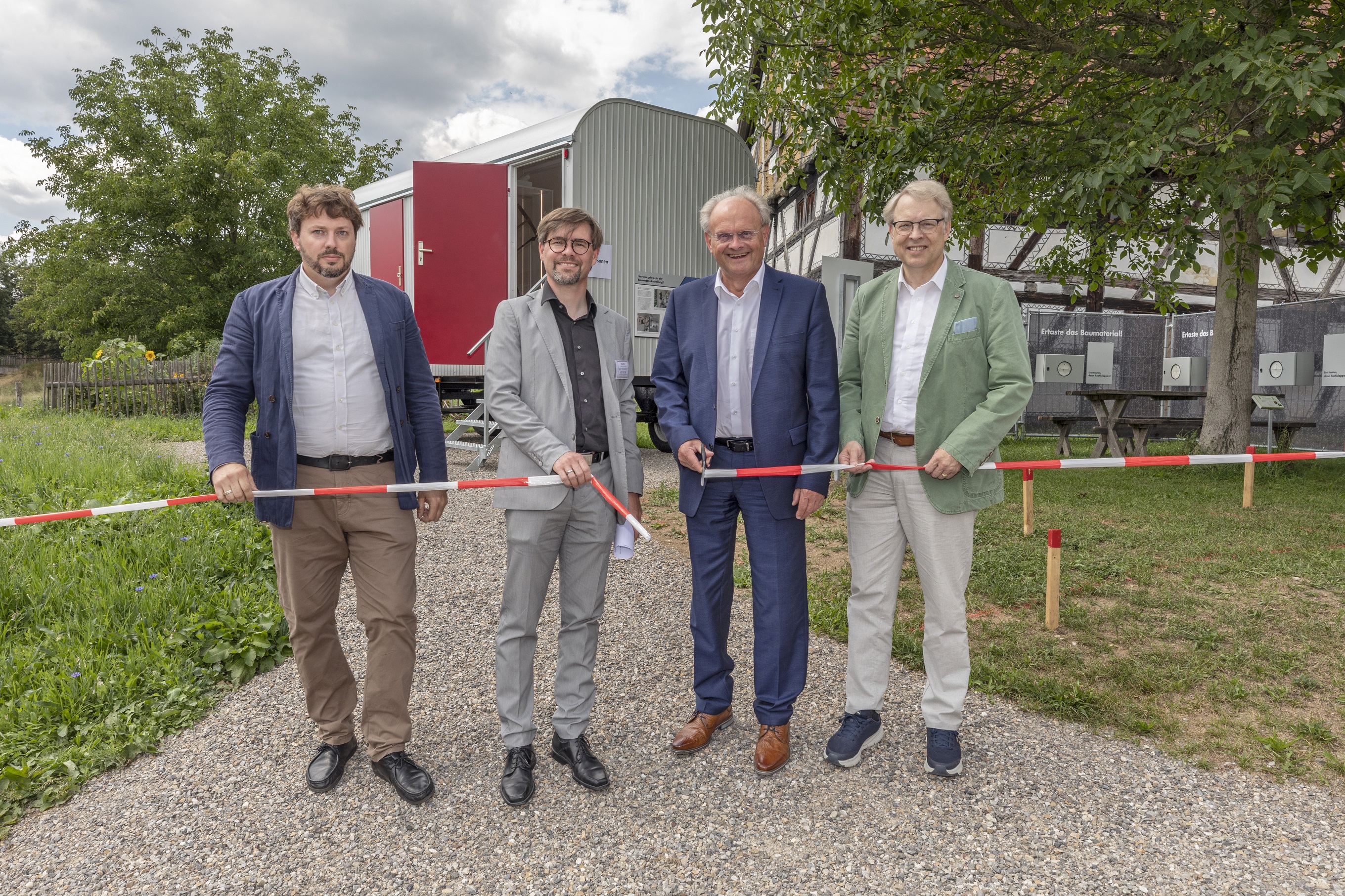 Das Bauabsperrband wird durchtrennt, der Bauwagen ist für die Besucher geöffnet und das angrenzende Freigelände, v.l.n.r. Philipp Scheitenberger M.A. (Kurator Ausstellung), Dr.-Ing. B. Niethammer (Museumsleiter Bauernhofmuseum Illerbeuren), Alfons Weber (Bezirkstagsvizepräsident), Dr. Stephan Winter (Stv. Landrat Ldkr. Unterallgäu)