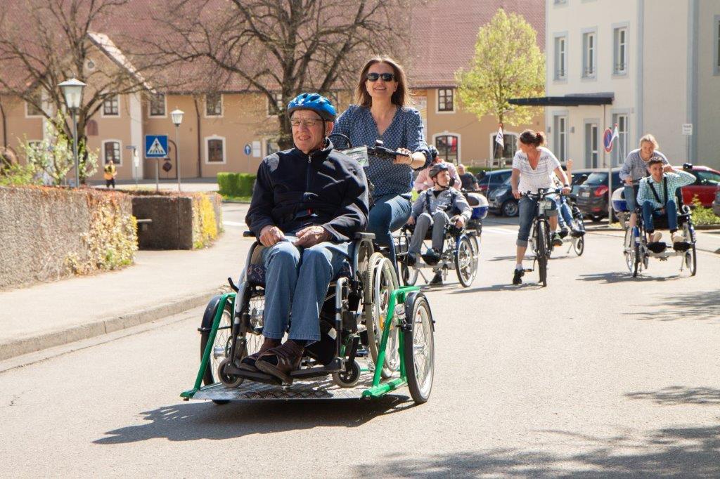 Menschen mit und ohne Behinderung fahren mit verschiedenen Fahrrädern