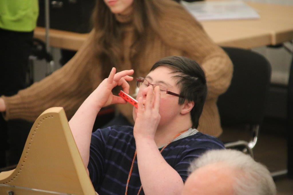 eine Frau mit Trisomie 21 spielt Mundharmonika