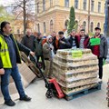 Paletten mit Hilfsgütern vor einem Lastwagen, daneben lächelnde Männer