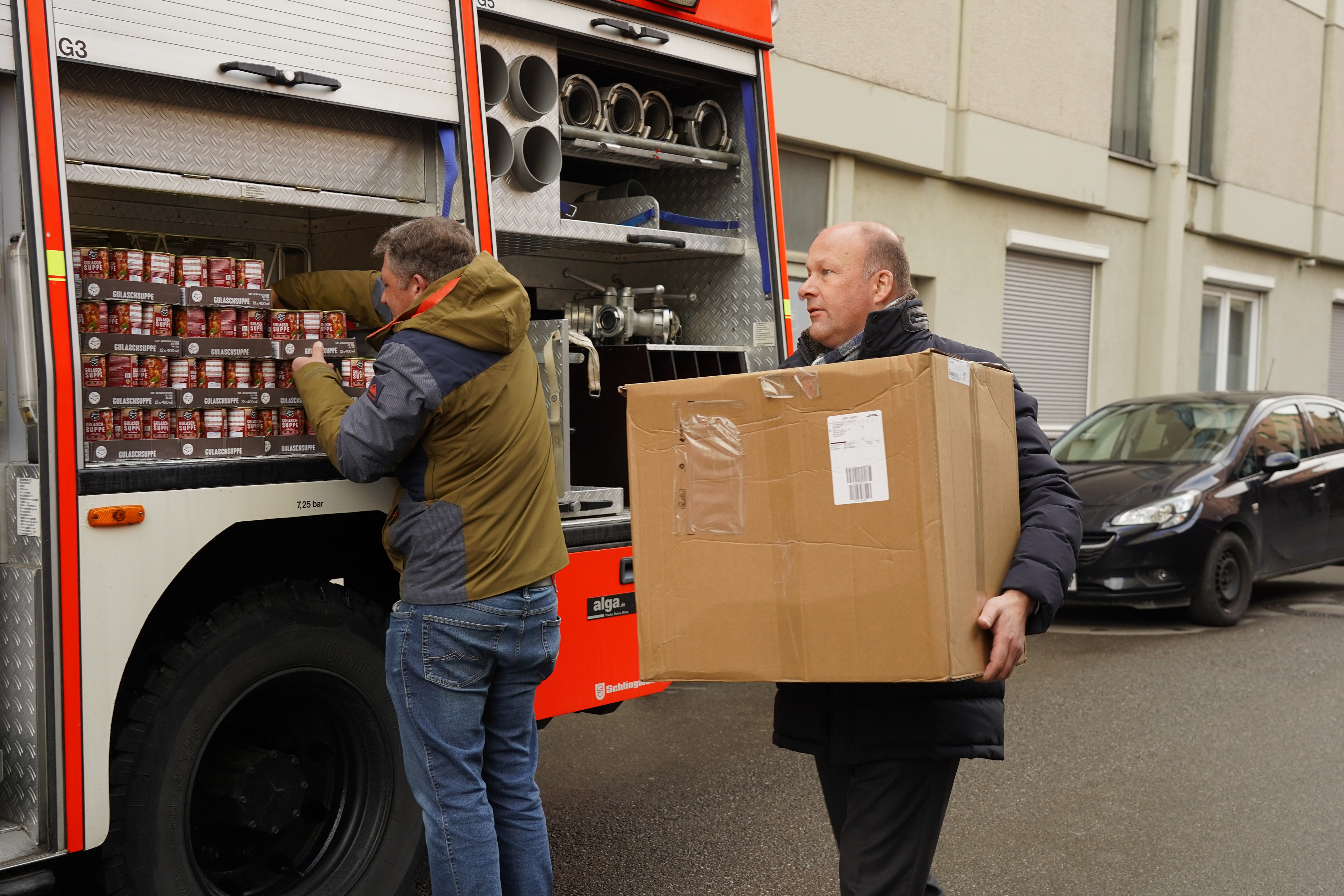 Mitarbeitende der Bezirksverwaltung und Bezirkstagspräsident Martin Sailer (rechts) verladen Winterkleidung, medizinischen Hilfs- sowie Nahrungsmitteln für die ukrainische Partnerregion Tscherniwzi. - Foto: Elisabeth Heisig