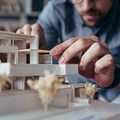 Hände eines Architekten an einem Hausmodell arbeitet