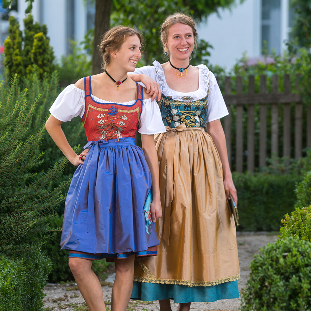 Zwei junge Frauen tragen ein Mädle-Gwand in verschiedenen Farben und unterschiedlicher Länge